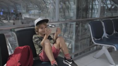 Ayrılış öncesi havaalanında akıllı telefonda sevimli çocuk video sohbetler.