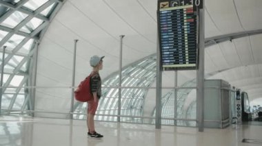 Young backpacker checking flight information on digital schedule display