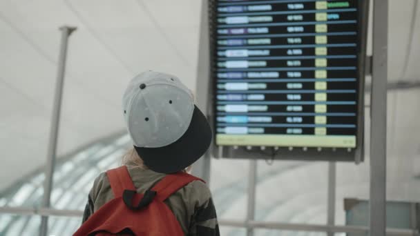 Junger Backpacker überprüft Fluginformationen auf digitaler Flugplananzeige — Stockvideo