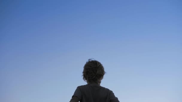 Παιδί σιλουέτα, υψώνοντας τα χέρια στον αέρα σε φόντο μπλε του ουρανού — Αρχείο Βίντεο