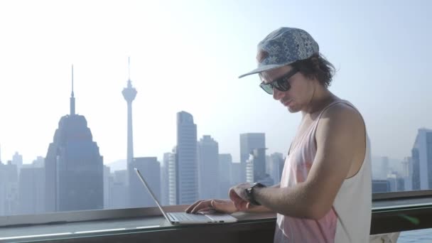 Freelancer con portátil en el fondo moderno de la ciudad durante las vacaciones de verano . — Vídeos de Stock