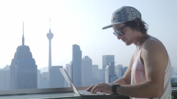 Freelancer usando laptop no fundo da cidade moderna durante as férias de verão . — Vídeo de Stock