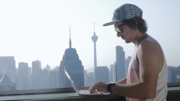 Freelancer con portátil en el fondo moderno de la ciudad durante las vacaciones de verano . — Vídeos de Stock