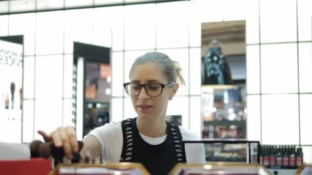 Fiatal lány keres kozmetikumok az üzletben. — Stock videók