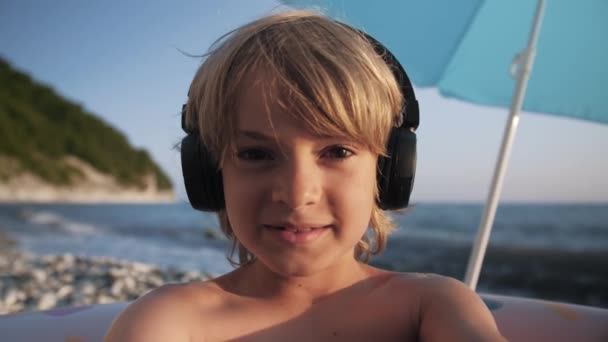 Bambino carino utilizzando lo smartphone sulla spiaggia — Video Stock