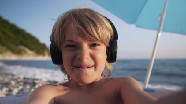 Schattig kind video chats op slimme telefoon op het strand — Stockvideo
