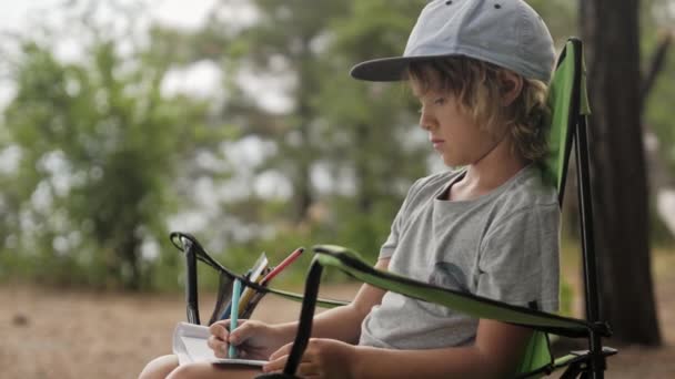 아이는 나무 배경에 노트북에 스케치를 만든다. — 비디오
