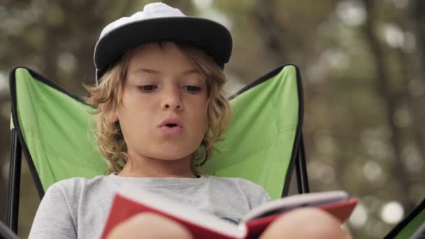 Portarit d'enfant lisant un livre sur fond de bois de pin . — Video