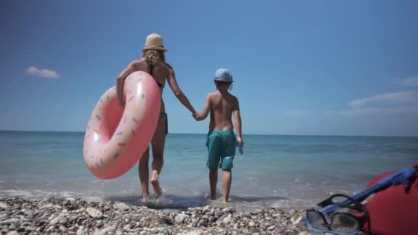 Happy young girl with child going to swim in blue sea. — Stock Video