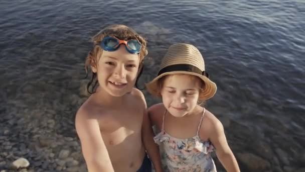 Cute children video chats on smart phone on beach — Stock Video