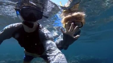 Balıklar ile berrak mavi okyanus suyunda baba ile şnorkel çocuk dalış