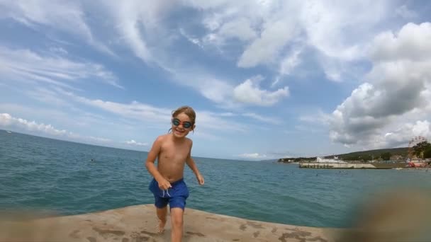 Niño corriendo y saltando del muelle en agua de mar . — Vídeos de Stock