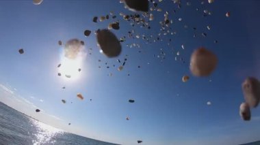 İnsan elinin deniz suyuna taş atmasına yaklaş..