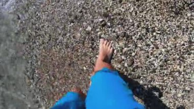 POV çocuğu, elinde yüzmek için bardaklarla denize doğru yürüyor.