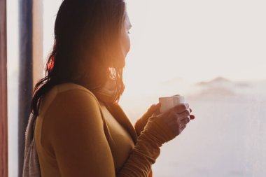 kadın bir terasta plajda gün batımında taze kahve sahiptir. Kapalı yaşam tarzı, arka görünüm