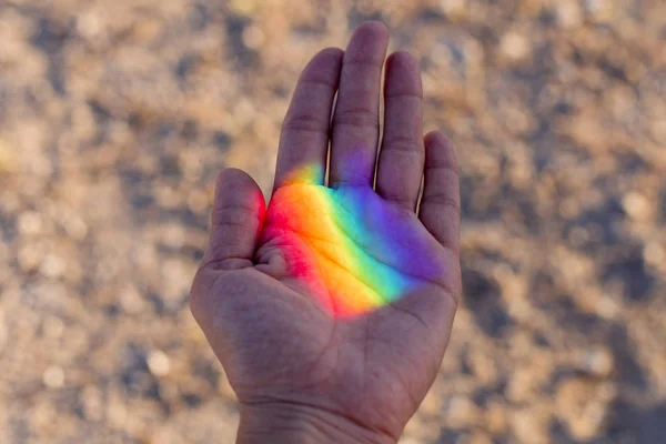 Üzerinde renkli gökkuşağı yansıması olan insan eli. Dışarıda gün batımı. Gurur günü konsepti. Lgbt aşk aşktır