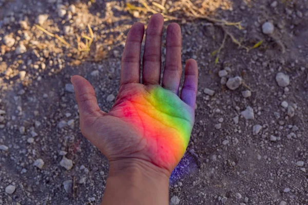 Human hand with colorful rainbow reflection on her. Sunset outdoors. Pride day concept. LGBT love is love