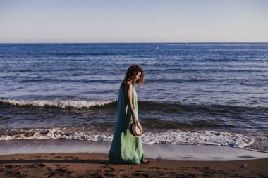 gün batımında sahilde yürüyen genç güzel kadın. Relax ve tatil kavramı