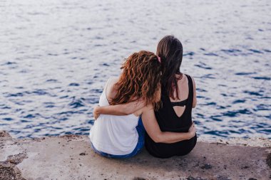 sahilde oturan iki kadın arkadaş kucaklıyor. yaşam tarzı kavramı açık havada