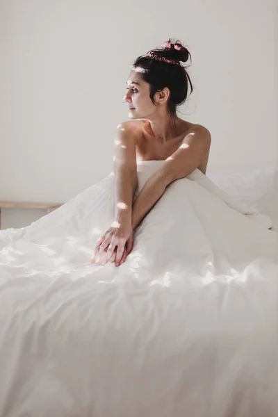 Жінка Вкрита Білими Простирадлами Сидять Ліжку Сонце Проходить Крізь Вікно — стокове фото