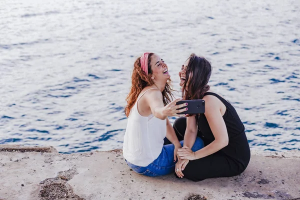Dua Teman Wanita Duduk Pantai Menggunakan Ponsel Mengambil Foto Selfie — Stok Foto