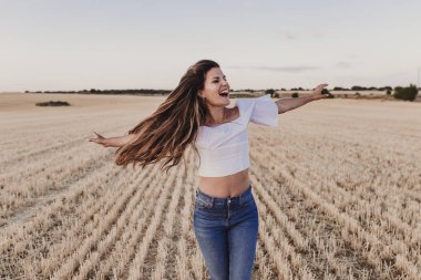 Summer Girl sarı alanda doğanın tadını çıkarıyor. Güzel genç kadın açık havada dans ediyor. Rüzgarda uzun saçlar. Mutluluk ve yaşam tarzı. Geri görünüm