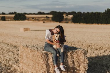 gün batımında sarı bir alanda onu altın retriever köpek ile yürüyüş genç güzel kadın. Doğa ve yaşam tarzı açık havada