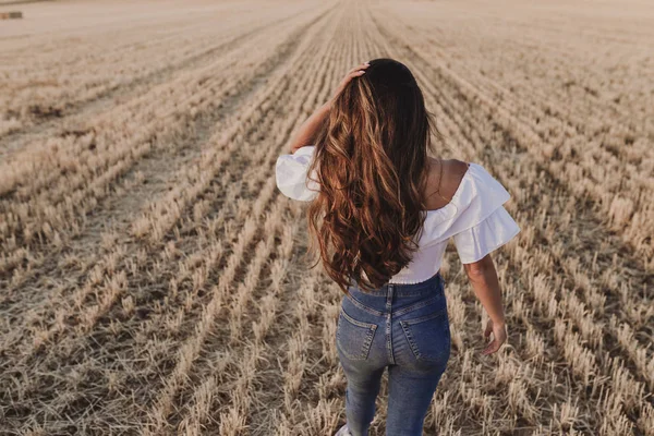 Summer Girl sarı alanda doğanın tadını çıkarıyor. Açık havada yürüyen genç ve güzel bir kadın. Mutluluk ve yaşam tarzı. Geri görünüm