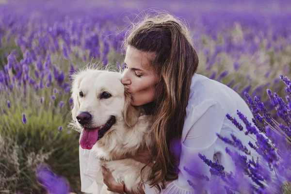 gün batımında lavanta tarlalarında onu altın retriever köpek öpüşme güzel kadın. Evcil hayvanlar ve yaşam tarzı.
