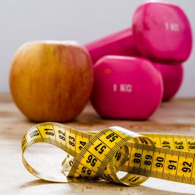 Natürmort ve elma, pembe ağırlık, sarı şerit metre ile yakın. Fitness ve yaşam tarzı kavramları.