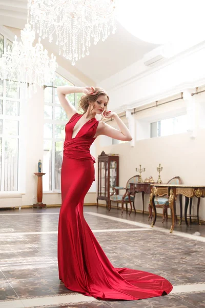 クラシックな内装のエレガントな赤いドレスで美しい女性 — ストック写真