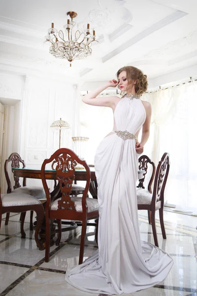 Portrait of an elegant bride in a Greek dress in a classic interior.