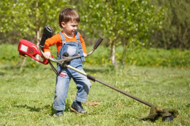 Küçük bir çocuk yerde düzeltici bir güneşli yaz günde mows..
