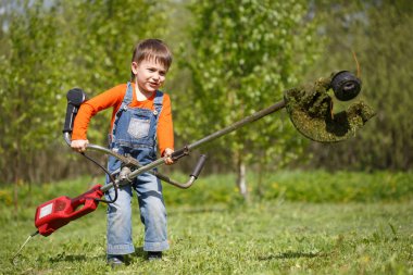 Küçük bir çocuk yerde düzeltici bir güneşli yaz günde mows..