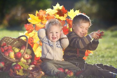 Sepet elma ile güneşli sonbahar gününde oynayan iki mutlu çocuk