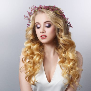 Heather gri bir arka plan üzerinde izole bir çelenk içinde şık bukleler ile sarışın kız güzellik portresi.