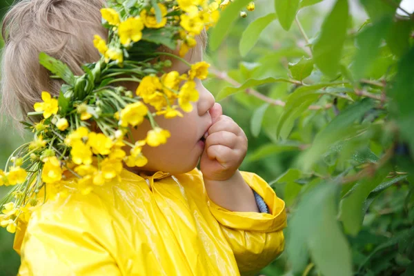黄色のレインコートとキンポウゲの花輪で小さな子供を食べる ブッシュからの果実 — ストック写真