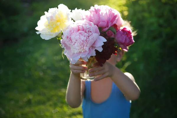 野外でピンクの牡丹の大きな花束を保持しているかわいい赤ちゃん — ストック写真
