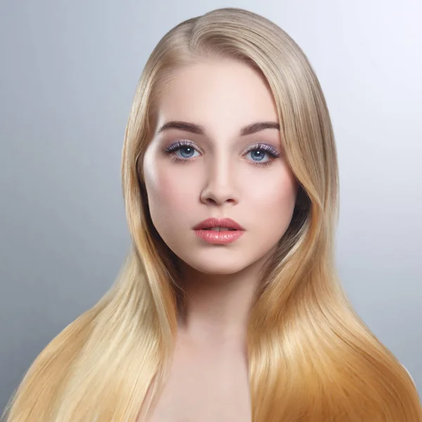 Güzellik Portresi gri bir arka plan üzerinde bakımlı izole uzun düz saçlı tatlı bir sarışın.