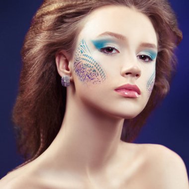 Mavi arka plan desenleri ile yaratıcı makyaj kız portresi.