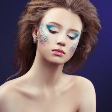 Mavi arka plan desenleri ile yaratıcı makyaj kız portresi.