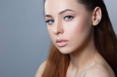 Gri arka plan üzerinde doğal makyaj güzel kız portresi.