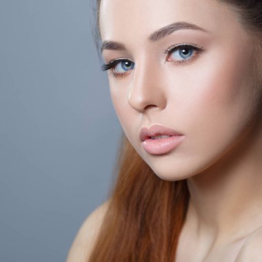 Gri arka plan üzerinde doğal makyaj güzel kız portresi.