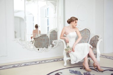 Aynada yansıması ile lüks bir koltukta oturan sevimli gelin.