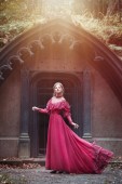 Картина, постер, плакат, фотообои "beautiful woman in vintage burgundy dress with flying train on a background of a gothic arch.", артикул 207344768