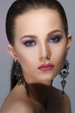 Gri bir arka plan üzerinde izole bir leylak makyaj güzel bir kızla moda güzellik portresi.