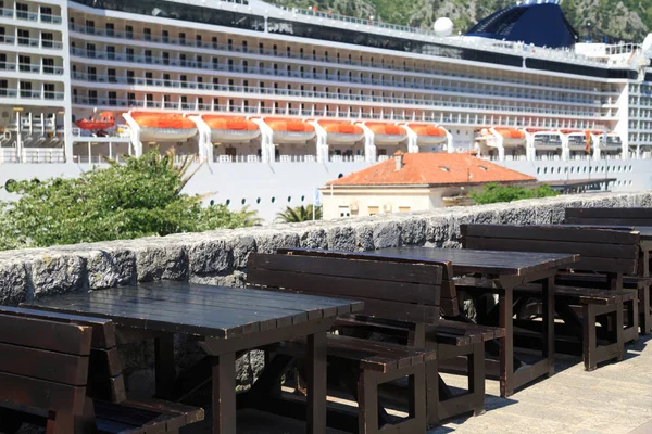 Open cafe with wooden furniture on the background of the ferry, Montenegro.