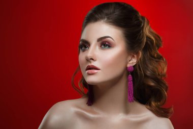 Parlak bir makyaj ve kırmızı bir arka plan üzerinde şık bir saç modeli ile güzel bir kız moda güzellik portresi.