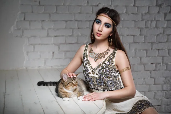 Beautiful girl in the image of Egyptian Cleopatra with a cat.