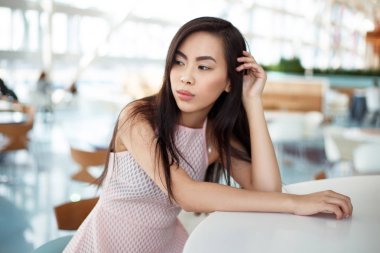 Pembe elbiseli kafede masada oturan dalgın Genç Asyalı kadın